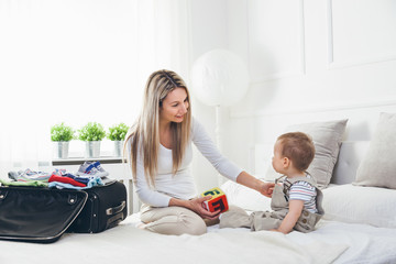 Wall Mural - Travelling with kids. Happy mother with her child packing clothes for holiday