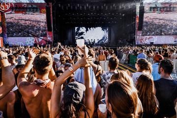 Music festival outside, mass world event, many spectators near the stage listen to the musician's performance. Bright colors, summer festival, dance party, real emotions. Hands up, singer, concert