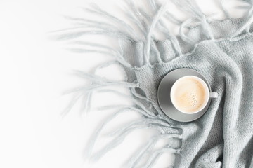 Cozy home composition, fluffy pastel light plaid, cup of coffee on white background. Christmas, New Year, winter concept. Flat lay, top view, copy space 