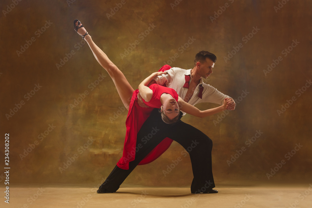 Flexible young modern couple dancing tango in studio. Fashion portrait of attractive dancing couple. Man and woman. Passion. Love. perfect skin facial and make-up. Human emotions - love and passion - obrazy, fototapety, plakaty 