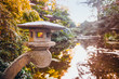 Close up stone Lantern in japanese style garden with pond and autumn trees. Traditional japan architecture. Exterior design, outdoor decor. Relax and mind calm concept. Selective focus. Copy space.