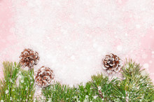 Christmas Background, Green Pine Branches, Cones Decorated With Snow On Snowy Pink Background. Creative Composition With Border And Copy Space Design Top View. New Year's, Holiday, Decoration
