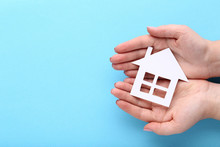 Female Hands Holding Paper House On Blue Background