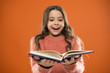 Child enjoy reading book. Book store concept. Wonderful free childrens books available to read. Childrens literature. Reading activities for kids. Girl hold book read story over orange background