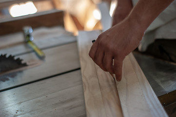 carpenter makes a markup using a tape measure and a pencil