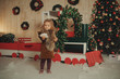 Happy little child girl sitting on a Christmas wooden train, decorated with Christmas tree branches and balls. Holiday concept