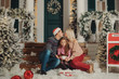 Holiday family couple on the Christmas porch of their house . Sitting outdoor with little child girl. Happy people kissing and hugging