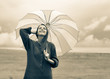 © Masson - Beautiful adult girl in sweater with umbrella at wheat field and cloudscape on background. Image in sepia color style