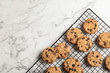 © New Africa - Cooling rack with chocolate chip cookies on marble background, top view. Space for text