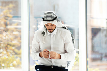 Wall Mural - Muslim man with misbaha praying near windows indoors