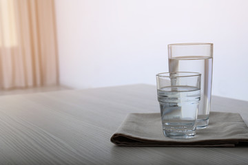 Glasses of water on table against blurred background. Space for text