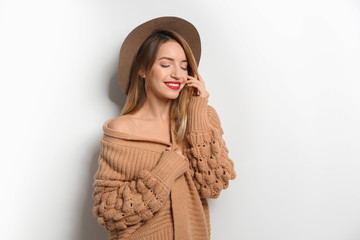 Wall Mural - Beautiful young woman in warm sweater with hat on white background. Space for text