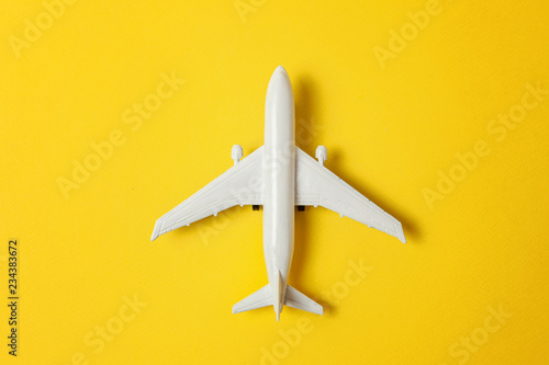 Fényképezés Simply flat lay design miniature toy model plane on yellow colorful paper trendy background