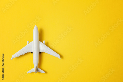 Fényképezés Simply flat lay design miniature toy model plane on yellow colorful paper trendy background