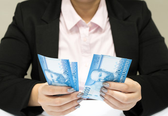 Close-up business woman wearing suit holding chilean money notes. Chile ten thousand (10000) pesos. Selective focus.