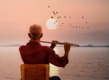 Man Playing Flute With Sunset Or Sunrise Background