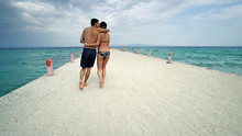 Romantic Couple In Bikini Walking On Beach Pier
