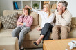 Sad worried parents in casual outfit puzzled about depression of teenage son who ignoring them, disappointed mother stroking head of son in living room