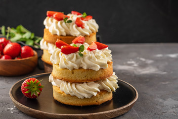 Victoria sponge cake with strawberries, jam and whipped cream on dark background. Copy space.