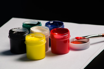 Multicolored cans of gouache with Paintbrush