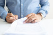 © Mangostar - Closeup of business man signing document. Business person sitting at desk. Agreement concept. Cropped front view.
