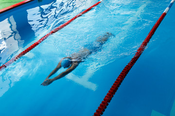 Wall Mural - Photo of sportsman in blue cap swimming on path in pool