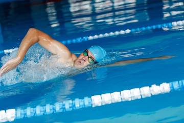 Sticker - Image of sportsman in blue cap swimming in style of crawl in swimming pool