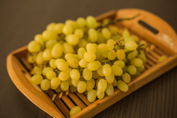 Wall Mural - Wooden tray with fresh ripe green grapes, close-up