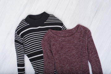 Burgundy and striped dress with sleeves on wooden background. Fashionable concept