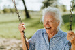 Leinwandbild Motiv Cheerful senior woman on a swing at a playground