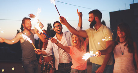 Friends enjoying a rooftop party and dancing with sparklers