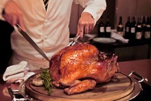 Professional Chef Carves A Whole, Roasted Turkey. An Impressive Centerpiece For Family Party, Easter, Thanksgiving, Christmas And New Year Celebration. Festive Holiday And Season Greeting. Warm Light.