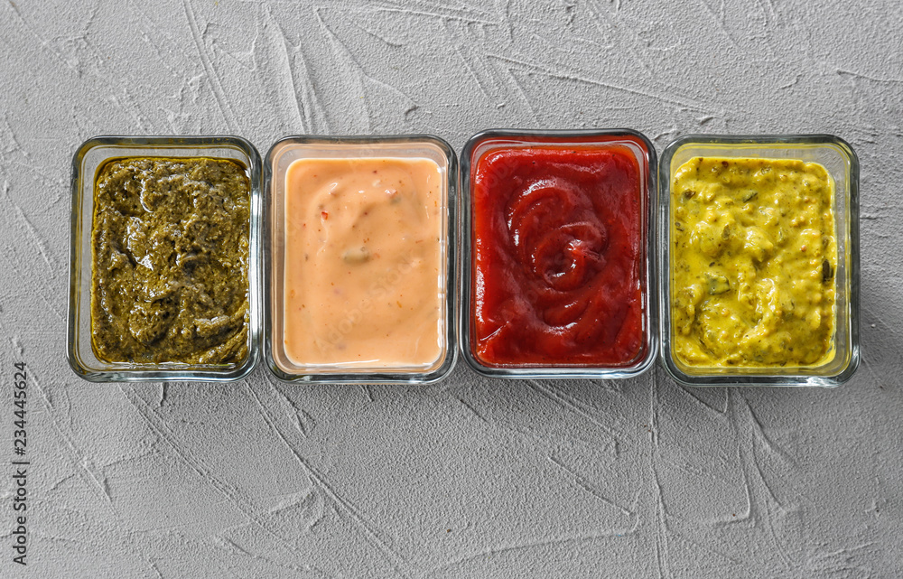 Different tasty sauces in bowls on grey background