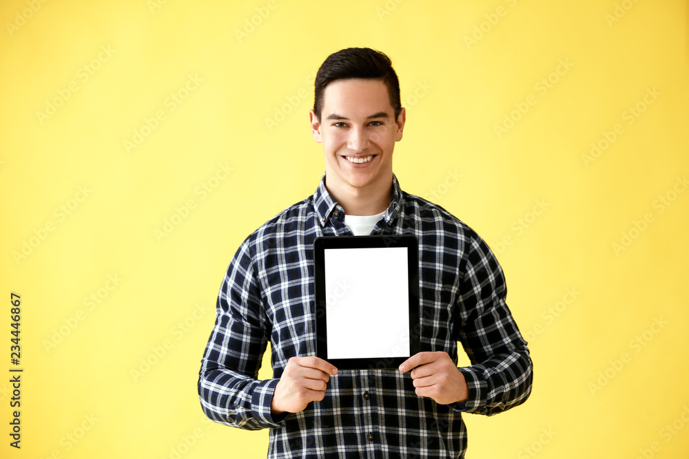 Young man with tablet computer on color background