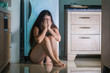 © TheVisualsYouNeed - young desperate and depressed woman at home kitchen floor crying scared victim of domestic violence and sexual abuse suffering depression and anxiety feeling helpless