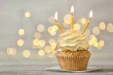 Delicious Birthday Cupcake With Burning Candles On Grey Table  Against Blurred Lights