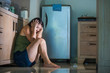 © TheVisualsYouNeed - young scared and desperate Asian Japanese woman crying helpless at home kitchen floor suffering domestic violence and sexual abuse victim of jealous husband
