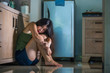 © TheVisualsYouNeed - young scared and helpless Asian Chinese woman horrified suffering domestic violence victim of abuse from drunk alcoholic husband at home kitchen floor crying