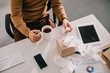 © LIGHTFIELD STUDIOS - cropped view of sick businessman holding cup of tea and box of tissues at office desk