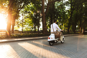 Poster - Young business man walking outdoors on scooter.