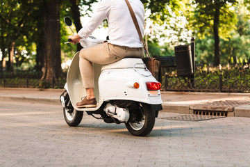 Poster - Young business man walking outdoors on scooter.