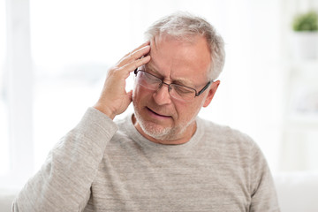 Wall Mural - health care, stress, old age and people concept - senior man suffering from headache at home