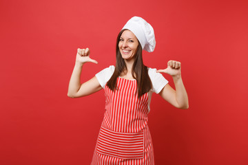 Housewife female chef cook or baker in striped apron white t-shirt toque chefs hat isolated on red wall background. Confident housekeeper woman pointing fingers on herself. Mock up copy space concept.