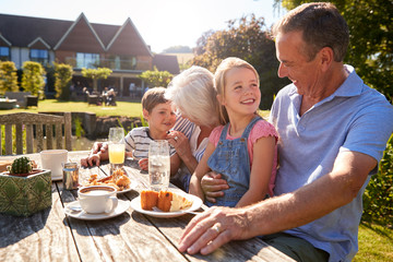 Grandparents With Grandchildren Enjoying Outdoor Summer Snack At Cafe