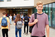 © Monkey Business - Portrait Of Smiling Male High School Student Outside College Building With Other Teenage Students In Background