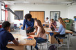 © Monkey Business - Teacher Talking To Female High School Student Sitting At Work Bench Using Laptop In Design And Technology Lesson