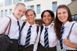 © Monkey Business - Portrait Of Smiling Female High School Students Wearing Uniform Outside College Building