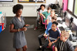 © Monkey Business - Teacher With Digital Tablet Talking To Line Of High School Students Sitting By Screens In Computer Class