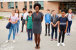 © Monkey Business - Portrait Of Smiling High School Student Group With Female Teacher Standing Outside School Buildings