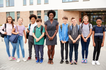 Wall Mural - Portrait Of Smiling High School Student Group With Female Teacher Standing Outside School Buildings